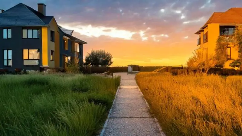 Zwei Haeuser gegenueber mit Weg dazwischen bei Sonnenuntergang - Entscheidung zwischen Mieten und Kaufen